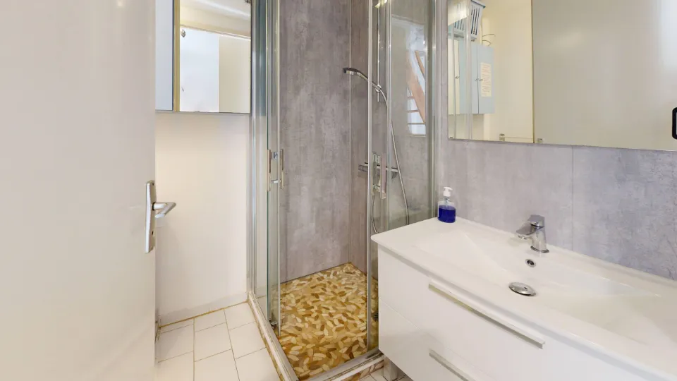 Salle d'eau avec cabine de douche, vasque et miroir, au 42 à Portiragnes-Plage